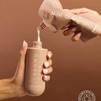 A hand holding and dispensing the Brown Bee gradual tan moisturizer bottle