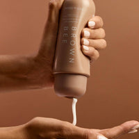 Gradual tan moisturizer being dispensed from the bottle into a cupped palm