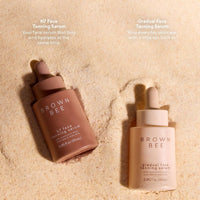 Two Brown Bee bottles standing together in sand
