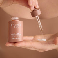 A dropper releasing H7 face tanning serum into an open palm