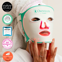 Omnilux Clear LED mask held up beside its FDA cleared, TGA approved and CE certified regulatory badges