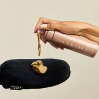 Self-tanning mousse dispensed from the bottle onto a black application mitt