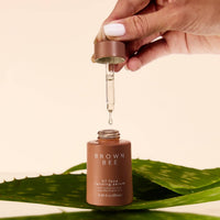A dropper held above the H7 serum bottle, which sits on a green aloe leaf